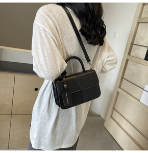 Detail of the black woven texture and leather finish on a stylish crossbody handbag