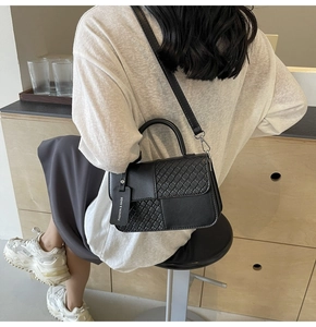 Detail of black woven texture bag with round handle and adjustable shoulder strap