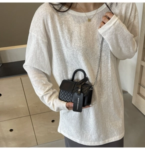 Detail of black woven texture mini handbag with gold chain strap and fashion tag