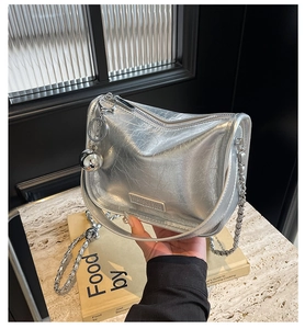 Détail du sac à bandoulière argenté métallisé avec texture plissée et chaîne à pendentif