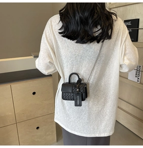 Detail of black quilted crossbody bag with silver chain and Fashion & Bags tag on model
