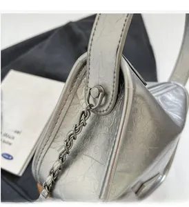 Gros plan sur la texture du cuir argenté et les détails de la chaîne en métal brillant du sac