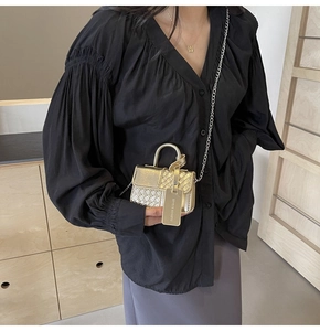 Detailed view of silver woven texture and metal chain strap on a stylish mini handbag