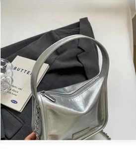 Détail du sac à main argenté métallisé avec texture plissée, poignée et chaîne décorative