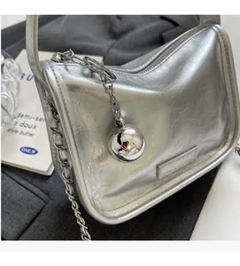 Détail du sac en cuir argenté froissé avec bandoulière chaîne et breloque boule