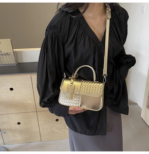 Detail of woven texture and gold metal ring handle on luxury crossbody handbag
