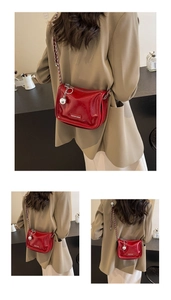 Détail du sac à bandoulière en cuir verni rouge avec chaîne argentée et pendentif en métal