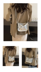 Détail du sac selle argenté métallisé avec bandoulière chaîne et pendentif boule