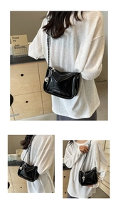 Détail de la sacoche en cuir verni noir avec chaîne argentée et charm sphérique décoratif
