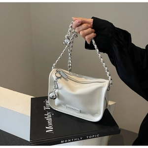 Détail du sac à chaîne blanc crème avec breloque boule en métal et étiquette de mode