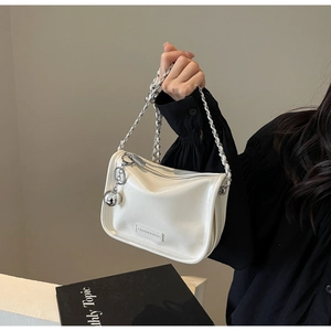 Détail du sac à épaule en cuir verni blanc avec chaîne argentée et pendentif en métal