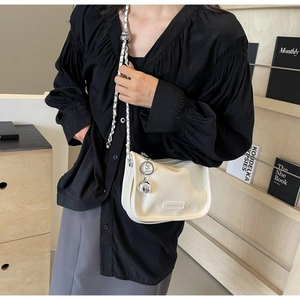 Détail du sac hobo blanc avec bandoulière tressée et breloque boule en métal argenté