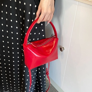 Glossy red leather handbag for women featuring a top handle and slim shoulder strap