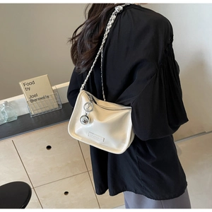 Détail du sac bandoulière blanc cassé avec chaîne argentée et charm boule en métal