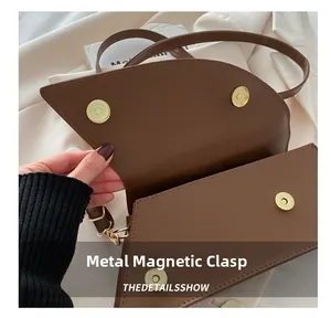 Dettaglio della chiusura magnetica dorata su una borsa a tracolla in pelle marrone