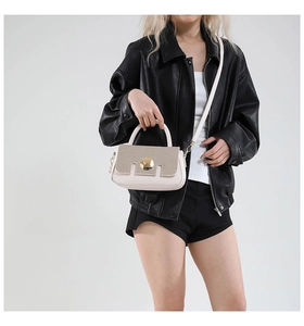 Detail of cream crossbody bag with brown woven flap and golden round turn-lock