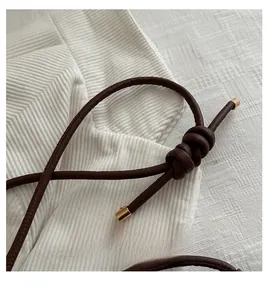 Detail of dark brown knotted shoulder strap with gold metal buckles and corduroy fabric