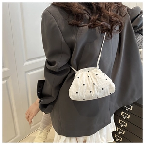 Détail de la texture du tissu blanc brodé de fleurs sur un sac seau souple