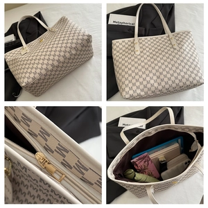 Detail view of large tote bag showing 'M' print, metal zipper and spacious interior