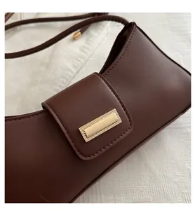Detail of dark brown leather baguette bag with a rectangle gold buckle and fine strap