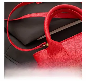 Detail of red lychee grain leather bucket bag showing hardware connection and shoulder strap