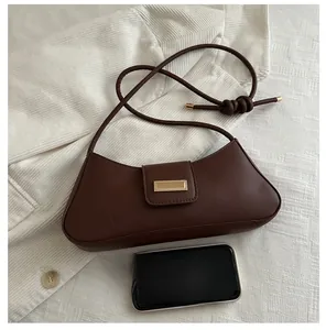 Deep brown baguette bag with golden buckle compared to a smartphone for scale