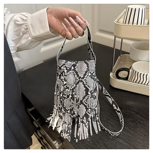 Detail view showing black and white snakeskin texture and long fringe on bucket bag
