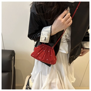 Détail d'un sac seau rouge à fleurs avec plis porté par un mannequin dans une pièce