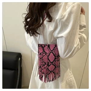 Pink and black snakeskin pattern crossbody bag with long fringe detail on white dress