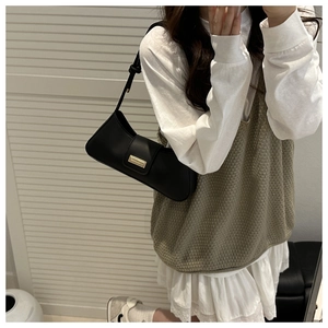 Model wearing a black French style baguette bag with a gold buckle and matte finish