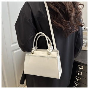 Detail of white leather handbag featuring Fashion Trend 1996 text and round handle