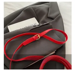 Detail of red lychee grain leather strap with adjustable golden buckle for bucket bag