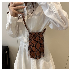 Close-up of brown snakeskin crossbody bag with long fringes and leather strap detail