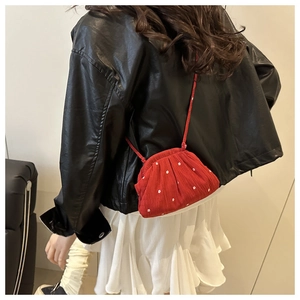 Détail du sac bandoulière en velours rouge avec broderie florale et sangle