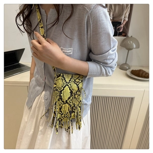 Detail of yellow snakeskin print mini bag with long fringe tassels and thin strap