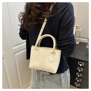 Litchi pattern cream white leather handbag shown crossbody from a rear side view on a model