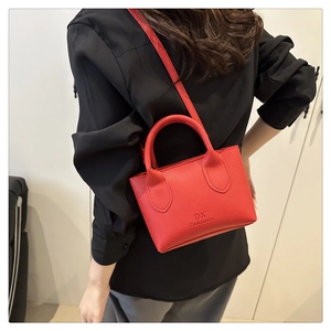 Detail einer roten Handtasche aus Leder mit DX-Logo und langem Schultergurt am Model