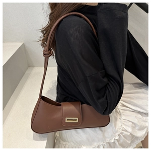 Close-up of a brown baguette bag with a gold buckle and knotted strap on a model