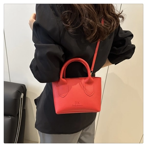 Detail showing red lychee leather texture and embossed logo on stylish mini tote bag