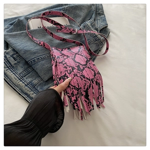 Detail of pink snake print crossbody bag featuring long bohemian tassels and silver buckle