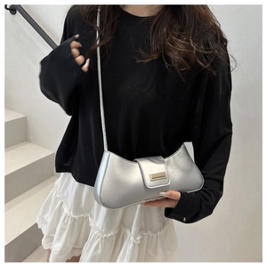 Silver crescent underarm bag with gold metal buckle shown on a model in a studio