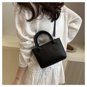 Detail of black pebbled leather crossbody bag with DX Do&Think embossed logo and straps