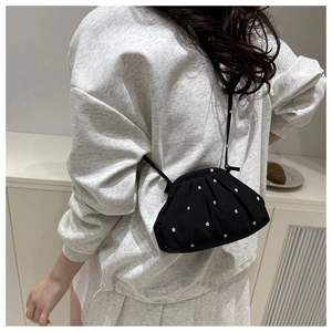 Détail du sac seau noir plissé à fleurs blanches porté par un mannequin en tenue décontractée