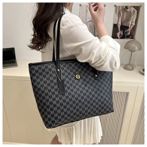 Detail van een grote shopper met M-monogrampatroon en een goudkleurig metalen logo
