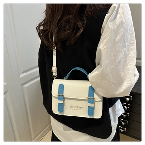 Detailed view of cream and sky blue crossbody bag with gold buckles on a model