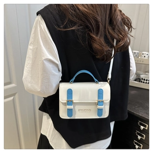 Detail view of a white rectangular crossbody bag featuring blue handles and gold hardware