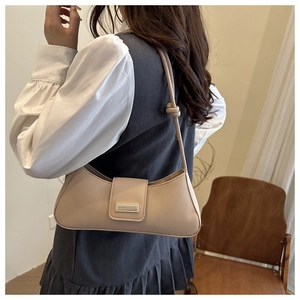 Detail of beige faux leather baguette bag with metal buckle and decorative strap knots