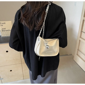 Détail du sac bandoulière en cuir blanc cassé avec chaîne argentée et breloque sphère