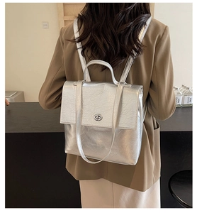 Détail du sac à dos argenté métallisé avec tissu texturé et boucle de fermeture rotative