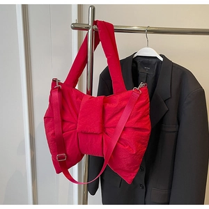 Detail of red bow-shaped quilted nylon bag with silver hardware and adjustable strap